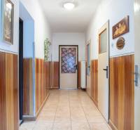 A hallway in a family house with wooden paneling and decorative pictures on the walls.