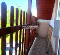 A wooden balcony with a railing on a cottage in Hontianske Trsťany, overlooking the garden.
