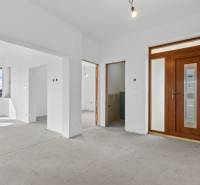 The interior of a family house with white walls, wooden doors, and a concrete floor.