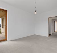 A room in a family house with white walls, a thick concrete floor, and balcony doors.