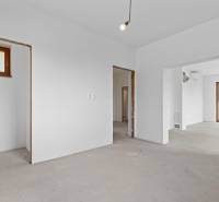 The interior of a family house with white walls, unfinished openings, and a window.