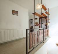 A hallway in a family house with wooden shelves and railing.