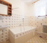 A bathroom in a family house with retro tiles and a bathtub, decorative flooring, and a radiator.