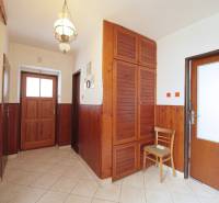 A hallway in a family house with wooden paneling, a cabinet, and tiles.
