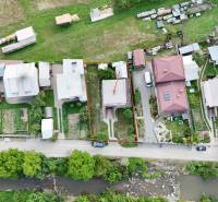 An aerial view of a row of family houses in Dolná Mariková with a river in the foreground.
