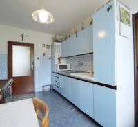 A kitchen in a family house with blue cabinets and ceramic tiles.