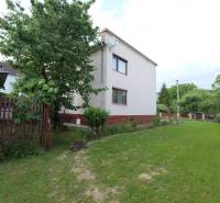 A family house in Dolná Mariková surrounded by a garden and a wooden fence on a grassy area.