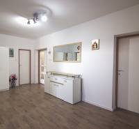Interior of a family house with white furniture, wooden decor flooring, and a large mirror.