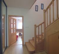 Interior of a family house with a wooden staircase, entrance to the living room, and storage space.