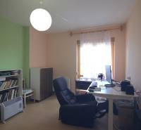 A study in a family house with a computer, a bookshelf, and a comfortable armchair.