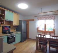 A kitchen in a family house with a kitchen unit, table, and chairs.