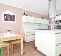 A kitchen in a 4-room apartment with a pink wall, a wooden table, and a modern kitchen unit.
