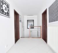 A hallway in a 4-room apartment with a staircase, paintings, and a radiator on the wall.