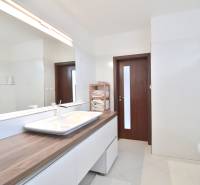 Bathroom in a 4-room apartment with a wooden cabinet, sink, and large mirror.