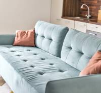 Light blue sofa and kitchen in a 3-room apartment with wooden flooring.