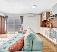 Living room with kitchen in a 3-room apartment, light sofa, wooden floor.