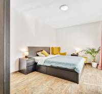 A bedroom in a 3-room apartment with a bed, nightstands, and a comfortable armchair.