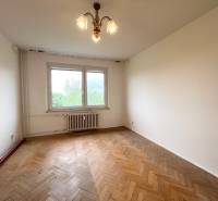 An empty room with parquet flooring and a large window in a 2-room apartment.