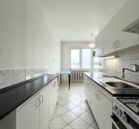 The kitchen in a 2-room apartment with white cabinets and black countertops.