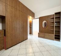 Interior of a 2-room apartment with wooden cabinets and a mirror on white tiles.