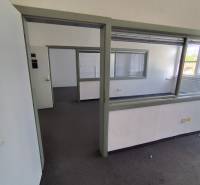 Offices with glass partitions and carpet, entrance through open doors.