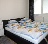 Bedroom in a 3-room apartment with a double bed, dresser, and window with black curtains.