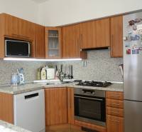 A kitchen in a 3-room apartment with wooden cabinets and stainless steel appliances.