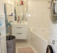 A bathroom in a 3-room apartment with a bathtub, sink, washing machine, and dryer.