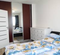 Bedroom in a 3-room apartment with a bed and built-in wardrobe, light walls and a dresser.