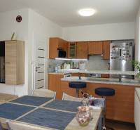 A kitchen in a 3-room apartment with wooden cabinets and a dining table.