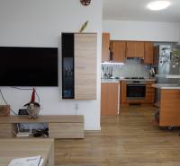 A kitchen with an island and a television in the living room of a 3-room apartment.
