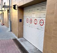 A garage door on a building with safety markings; near a concrete sidewalk.