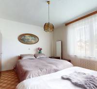 A bedroom in a family house with a wooden wardrobe, a large bed, and a decorative lamp.
