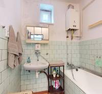 A bathroom in a family house with a bathtub, a sink, and a gas boiler.