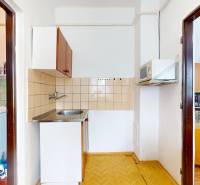 Interior of a family house with a kitchen, microwave, washing machine, and a shelf with books and dishes.