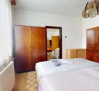 Bedroom in a family house with wooden wardrobes and white curtains.