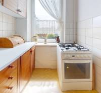 A kitchen in a family house with wooden cabinets, a stove, and a view from the window.