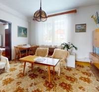 Living room in a family house with a carpet, sofa, armchairs, and a display cabinet.