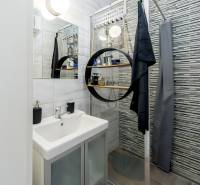 Bathroom with a sink, shower, and mirror, tiled with stylish tiles.