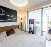 Bedroom with a bed, a picture of a bridge, and access to a balcony in a studio apartment.