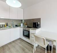 Kitchen in a studio apartment with white cabinets, a table, and appliances.