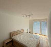 A bedroom in a two-room apartment with a bed and a nightstand, a spacious window with blinds.