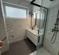 Bathroom in a 3-room apartment with white tiles and a glass shower enclosure.