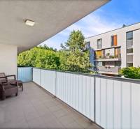 A spacious balcony in a 3-room apartment with a view of greenery and neighboring buildings.