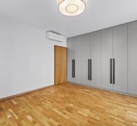 A spacious room with wooden flooring, a wardrobe, and air conditioning in a 3-bedroom apartment.