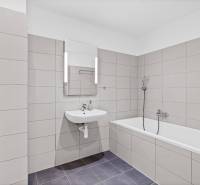A bathroom in a 3-room apartment with a bathtub and a sink, tiled with beige tiles.