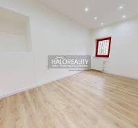 A bright office with wooden flooring and a red window frame.