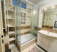 Bathroom of a 2-room apartment with a bathtub, sink, and shelf.