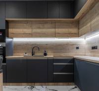 A kitchen unit with wooden paneling and black appliances in a 3-room apartment.