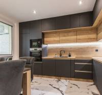 A kitchen in a 3-room apartment with wooden and black cabinets, marble floor.